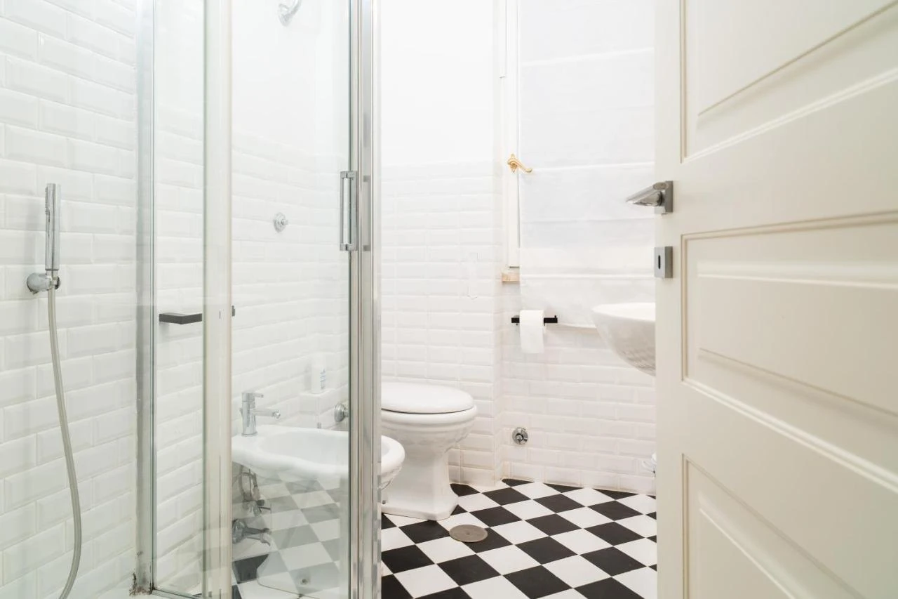 Il bagno con piastrelle bianche, doccia e pavimento a scacchi