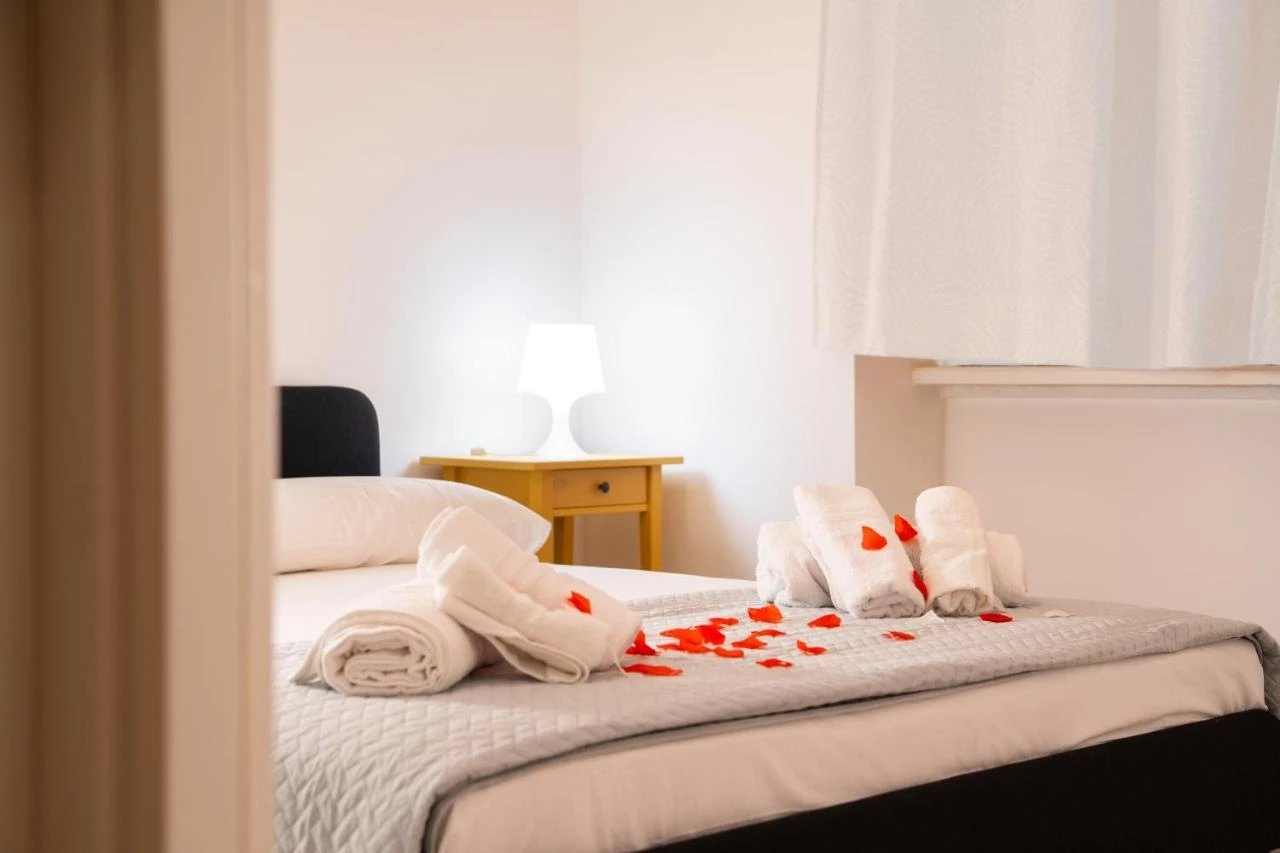 Il letto con asciugamani arrotolati e petali di rosa