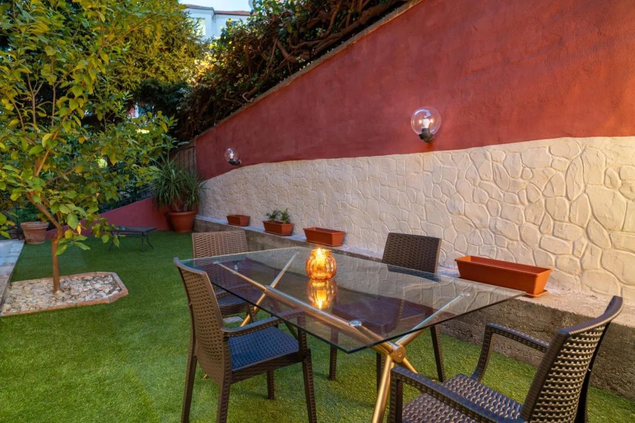 Il giardino al tramonto, con il tavolo di vetro, la candela accesa e il muro color terracotta