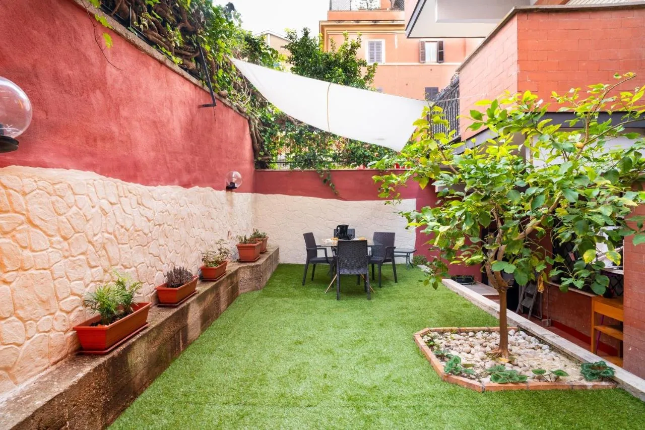 Il giardino con piante in vaso, un alberello e il tavolo in fondo