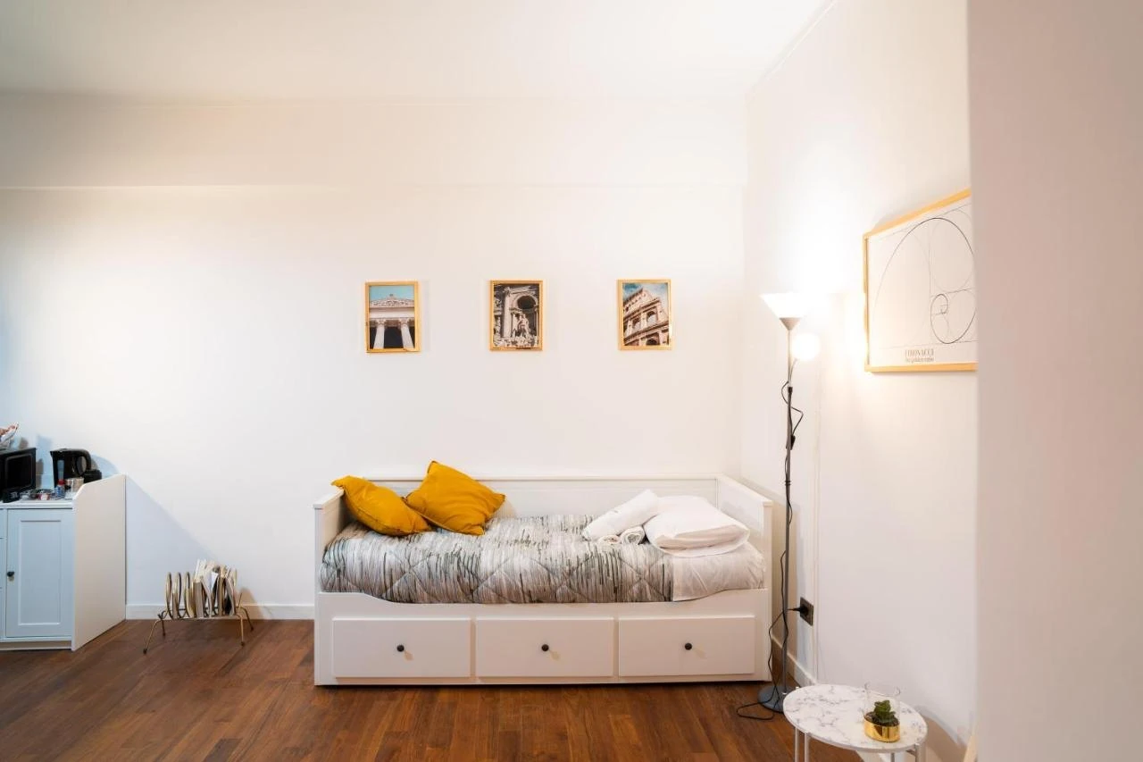 Il divano letto della sala, con cuscini color senape e quadretti alle pareti